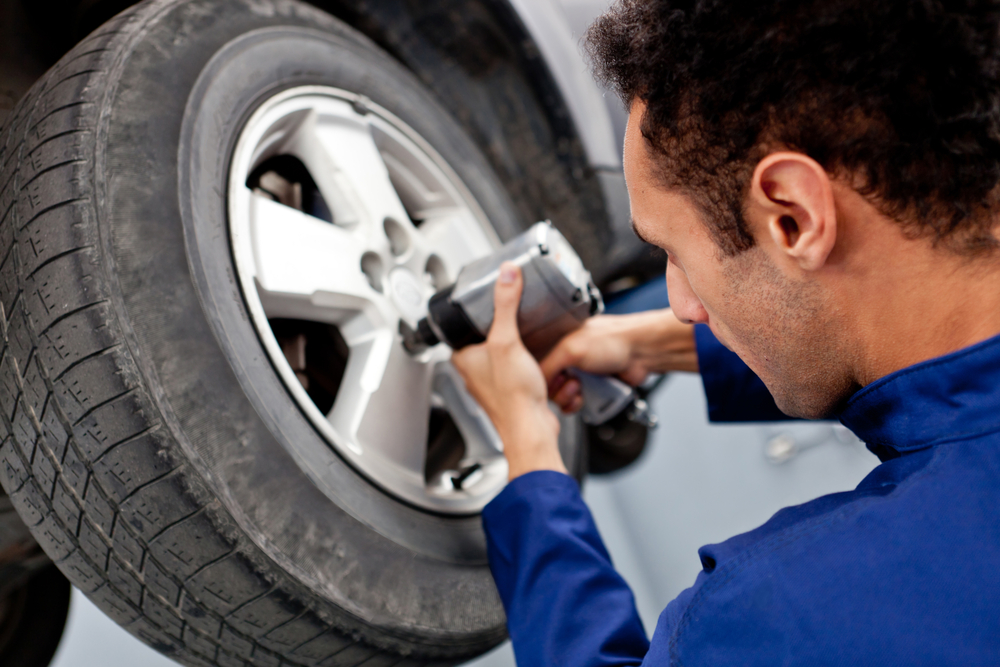Mechanic fixing a puncture on a car at the garage Mechanic fixing a puncture on a car at the garage
